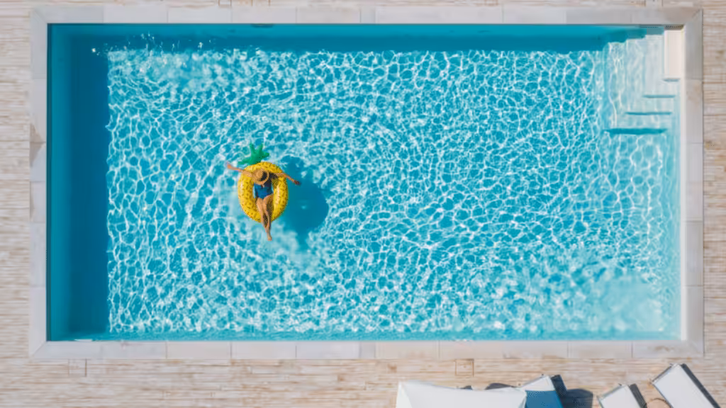 Femme sur une bouée ananas dans une grande piscine creusée bleu 
